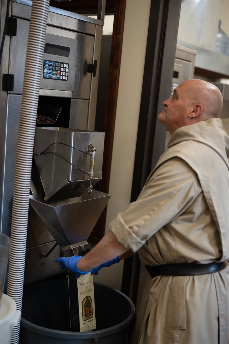 Benedictine monk filling a bag of Sanctus Coffee at the monastery